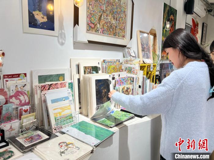 圖為藝術(shù)品商店內(nèi)，顧客挑選插畫作品?！＄婌?攝