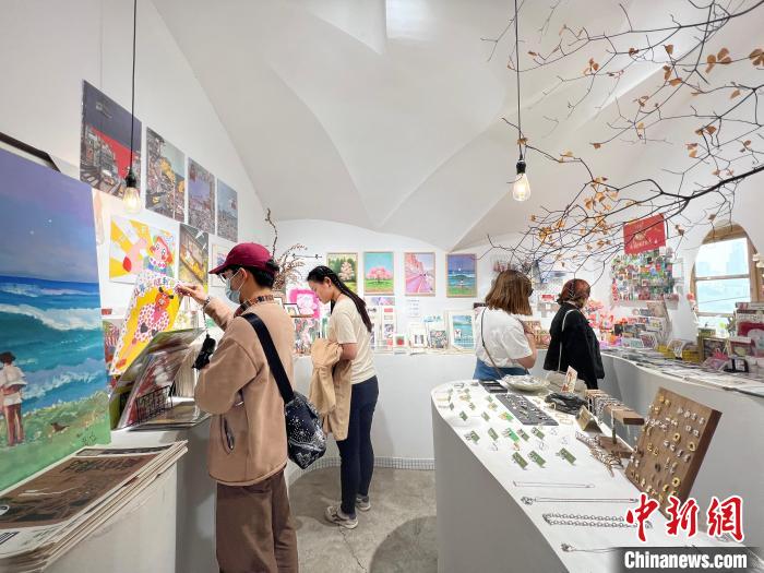 圖為藝術(shù)品商店內(nèi)，顧客挑選插畫作品?！＄婌?攝