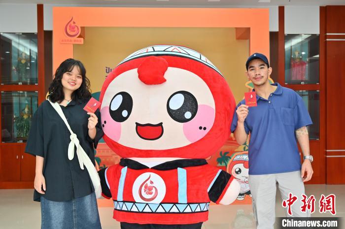 圖為泰國(guó)留學(xué)生手持獻(xiàn)血證與人偶合影。　俞靖 攝