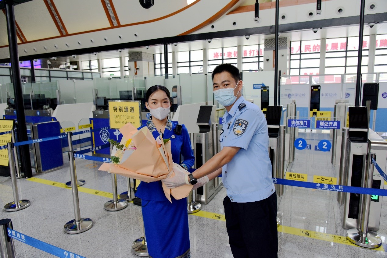 磨憨出入境邊防檢查站民警為中老鐵路第100萬(wàn)名出入境旅客，D888次國(guó)際旅客列車?yán)蠐爰藙?wù)員森達(dá)拉·妮緹婭（Sengdala Nitiya），送上鮮花。黃遠(yuǎn)飛 攝