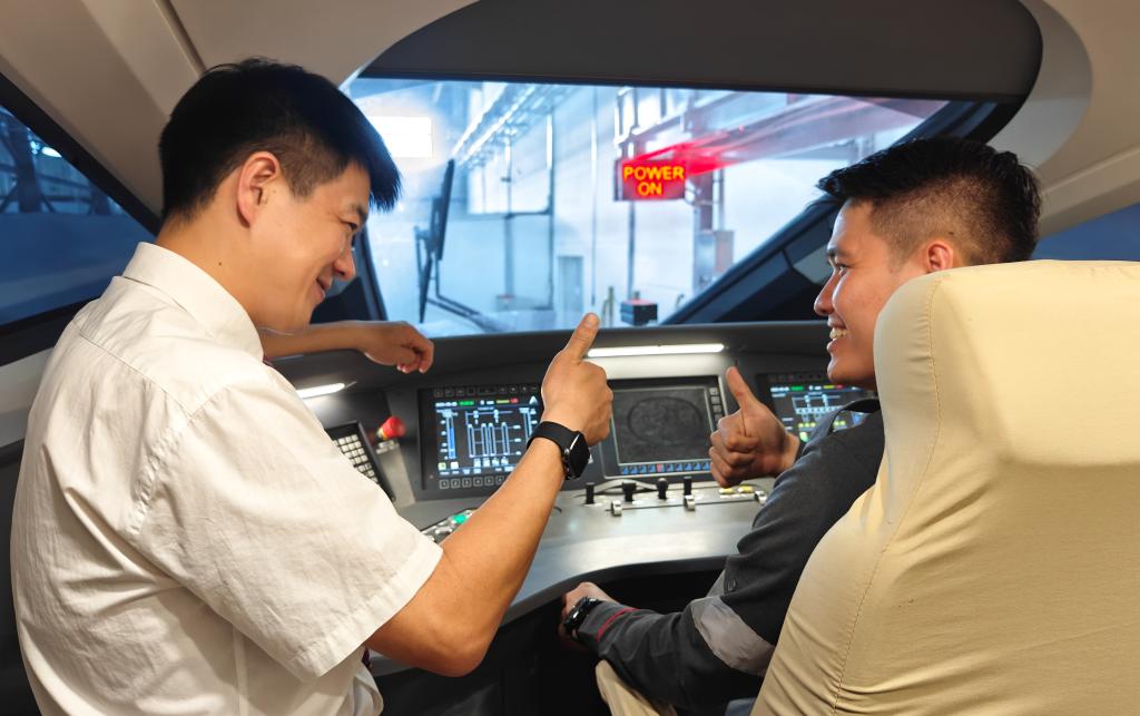 8月25日，在印度尼西亞萬隆的雅萬高鐵德卡魯爾動(dòng)車所內(nèi)，中國(guó)師傅穆振（左）在向印尼火車司機(jī)塞蒂亞萬講解動(dòng)車組出庫前的上電作業(yè)。