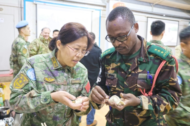 圖為維和官兵與外軍人員共同包餃子。胡光明攝