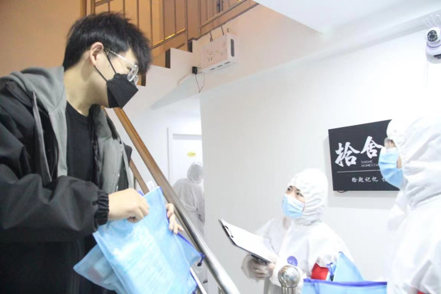 社區(qū)工作人員和志愿者身穿防護(hù)服上門(mén)送馬應(yīng)龍大健康防疫包。徐帥攝