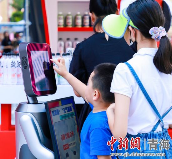圖為一名小朋友正在和機器人“志愿者”進行互動。 沐聞 攝