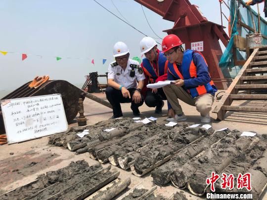 圖為勘察設(shè)計人員與海事局工作人員查看巖芯情況?！∥赫?攝