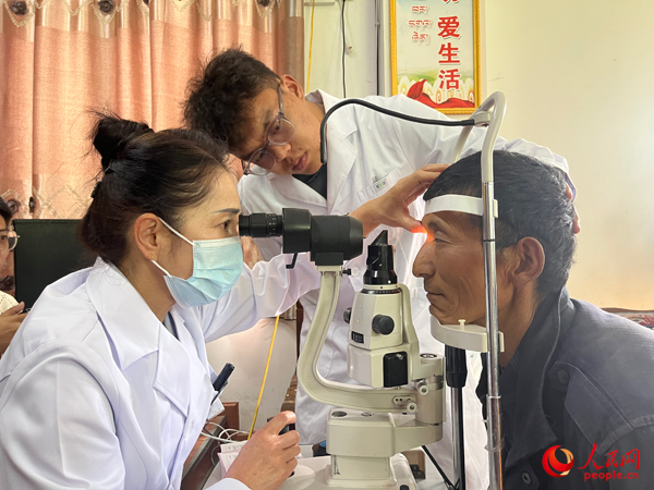 王紅英（左）和團(tuán)隊(duì)成員為達(dá)熱村村民檢查眼睛。人民網(wǎng)記者 杜燕飛攝