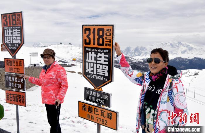 圖為5月14日，西藏林芝色季拉山觀景臺(tái)，游客與南迦巴瓦峰合影。　李林 攝