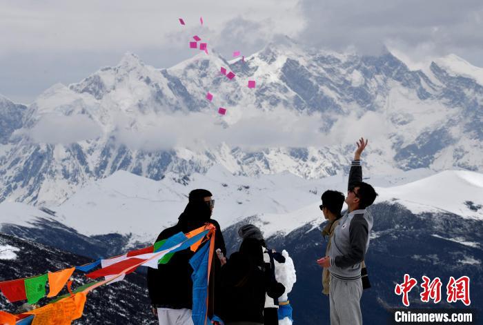 圖為5月14日，游客在西藏林芝色季拉山觀景臺(tái)拋灑“隆達(dá)”(風(fēng)馬旗，藏族民眾的一種祈福方式)?！±盍?攝