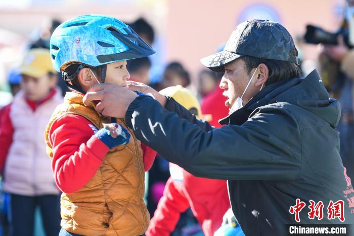 圖為拉薩市實(shí)驗(yàn)幼兒園孩子在教練的幫助下穿戴頭盔?！『闻罾?攝