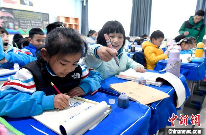3月14日，西藏拉薩市第一小學一年級六班學生白瑪朗珍(圖左)在藏語文課上書寫藏文。　李林 攝