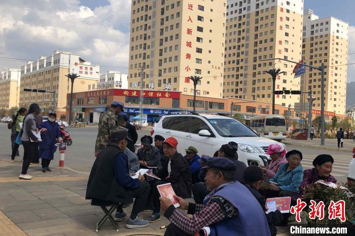 圖為會澤縣城易地扶貧搬遷安置點內(nèi)，老人們聚在廣場上聊天，身后是他們的新家?！】姵?攝