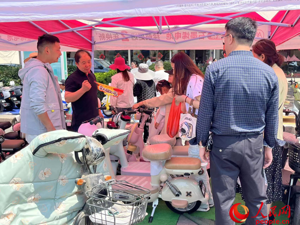 某電動(dòng)自行車(chē)品牌工作人員向消費(fèi)者介紹以舊換新相關(guān)情況。人民網(wǎng)記者 杜燕飛攝