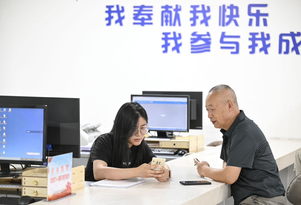 2024年6月20日，在寧夏銀川市金鳳區(qū)長城花園社區(qū)黨群服務中心，工作人員幫助居民辦理業(yè)務。圖片來源 新華社