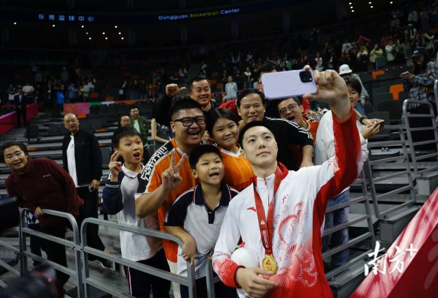 11月12日，十五運(yùn)會男籃成年組決賽，廣東隊(duì)獲得冠軍后，胡明軒與球迷們合影留念。張由瓊 攝