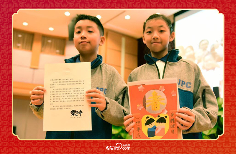 圖為香港“少年警訊”成員郭宏晞（左）展示習主席回信、羅顥凝（右）展示送給習主席的賀卡并合影。