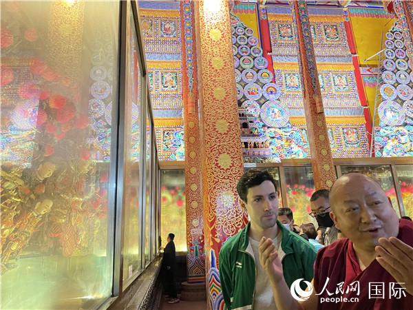 7月25日，省級非物質(zhì)文化遺產(chǎn)項目塔爾寺酥油花的代表性傳承人朋措堅參（右）在塔爾寺酥油花館講解酥油花的制作過程。人民網(wǎng) 謝瑩攝