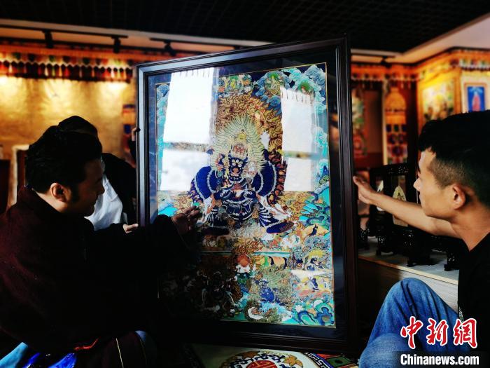 圖為久美尖措(左)與徒弟們展示唐卡作品?！?zhí)砀?攝