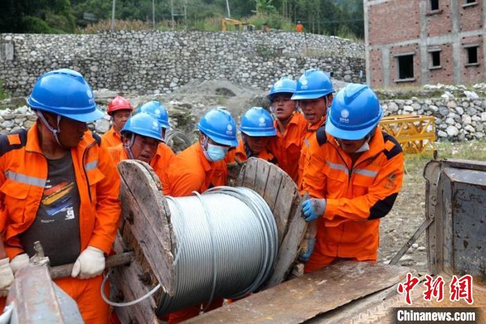 國網(wǎng)四川送變電公司搶險隊員將重達370公斤的鋼絞線搬上車?！⑾驸C 攝
