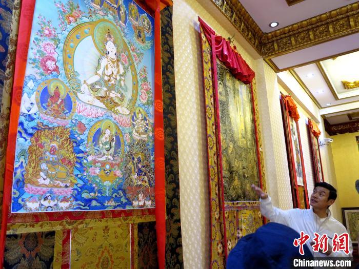圖為完德尖措展示熱貢龍樹畫苑內(nèi)的唐卡?！?zhí)砀?攝