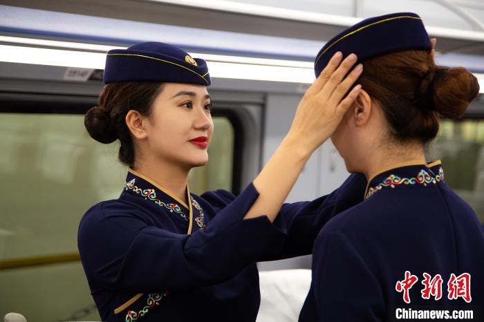 圖為青藏鐵路西格段“復(fù)興號(hào)”動(dòng)車組乘務(wù)員互相整理新制服?！±罾?攝