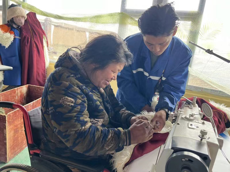扎西奪爾登幫助殘疾員工裁剪。阿壩州文明辦供圖