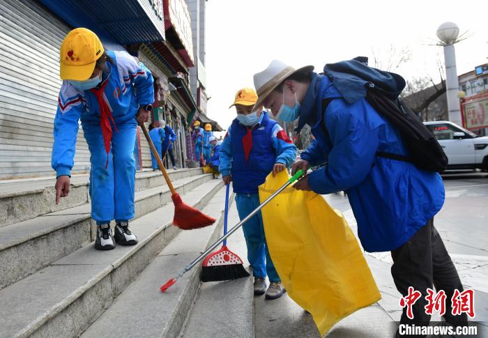 圖為拉薩市小學(xué)生打掃街道?！∝暩聛?lái)松 攝