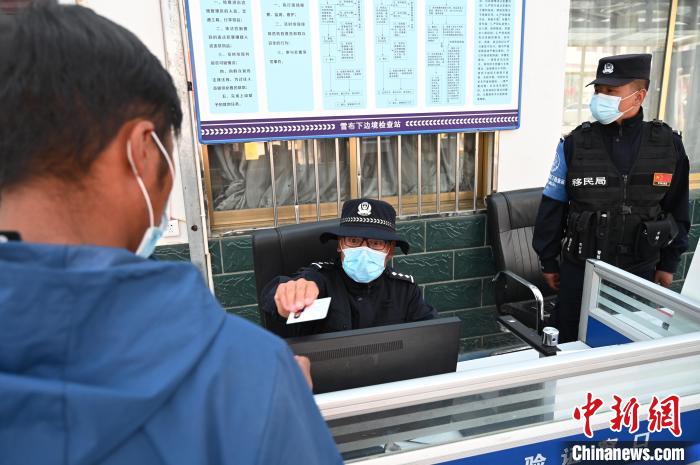 圖為移民管理警察登記完身份信息后將證件歸還給行人?！≮w朗 攝