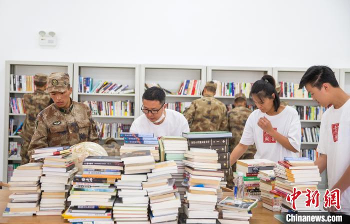 圖為志愿者們和邊防戰(zhàn)士整理圖書?！詵| 攝
