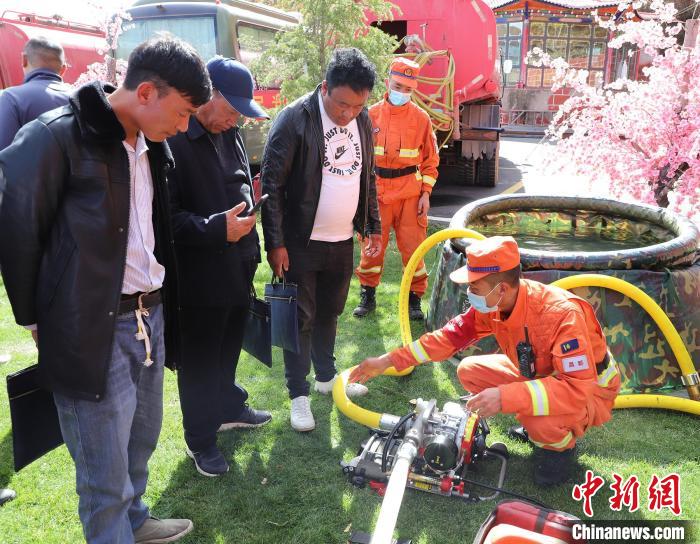 圖為森林消防員為護(hù)林員講解滅火裝備的使用方法?！〔际猩窒乐ш?duì) 供圖