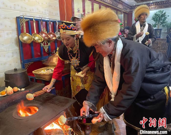 圖為人們在火上烤節(jié)日美食“結達”?！∪轿木?攝