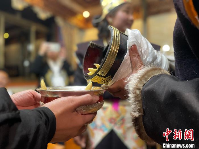 圖為主人在碗中斟滿青稞酒?！∪轿木?攝