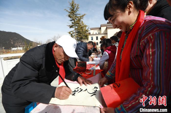 圖為林芝市文聯(lián)書(shū)法家協(xié)會(huì)會(huì)員向民眾贈(zèng)送藏文書(shū)法作品?！埩?攝