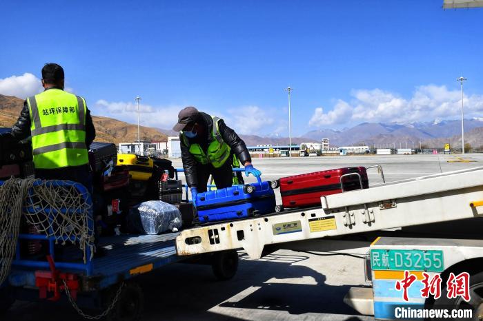 圖為機場工作人員傳送旅客行李箱?！≈芎?攝