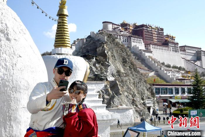 4月17日，游客身著藏式元素服裝在拉薩布達(dá)拉宮觀景臺拍照留念?！±盍?攝