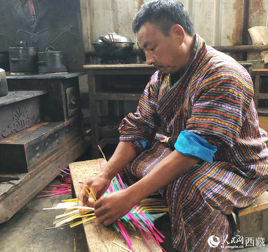 門(mén)巴族漢子愛(ài)明正在編織藤竹品。
