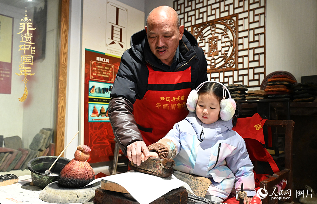 2025年1月27日，河南開(kāi)封朱仙鎮(zhèn)木版年畫(huà)藝人尹國(guó)法指導(dǎo)小朋友研習(xí)年畫(huà)印制技藝。朱仙鎮(zhèn)木版年畫(huà)源自漢唐壁畫(huà)藝術(shù)，是中國(guó)木版年畫(huà)的鼻祖。2006年5月20日，朱仙鎮(zhèn)木版年畫(huà)經(jīng)國(guó)務(wù)院批準(zhǔn)列入第一批國(guó)家級(jí)非物質(zhì)文化遺產(chǎn)名錄。人民網(wǎng)記者 王玉興攝