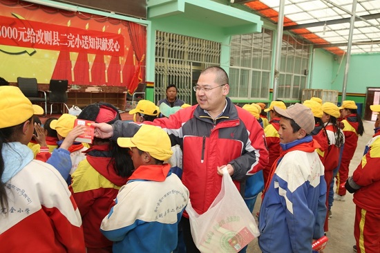 段玉平為孩子們分發(fā)愛心人士捐贈的新華字典 圖片來源：央廣網(wǎng).jpg
